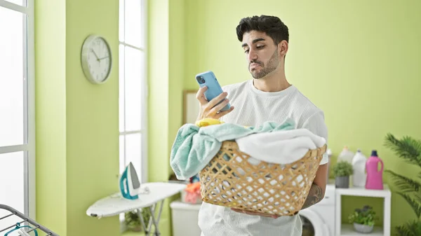 Çamaşırhanede Çamaşır Sepetini Akıllı Telefon Kullanarak Tutan Spanyol Bir Genç — Stok fotoğraf