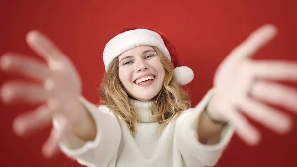 Młoda Blondynka Nosi Świąteczny Kapelusz Stojąc Otwartymi Ramionami Odizolowanym Czerwonym — Zdjęcie stockowe