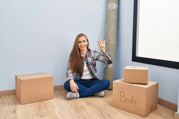 Mujer Rubia Joven Sentada Suelo Moviéndose Una Nueva Casa Mostrando —  Fotos de Stock