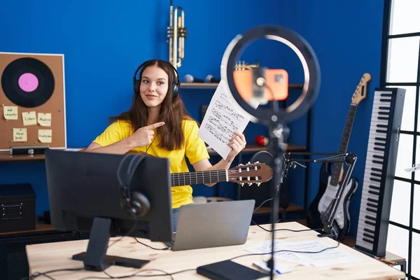 Young woman musician having online classical guitar class at music studio