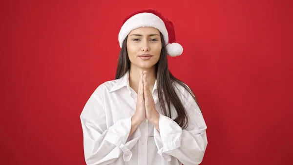 Молодая Красивая Латиноамериканка Улыбается Молясь Рождественской Шляпе Изолированном Красном Фоне — стоковое фото