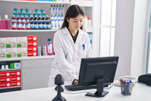 Chinese woman pharmacist using computer working at pharmacy