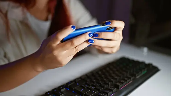 Game on! woman streamer\'s hands mastering video game on smartphone in gaming room at night