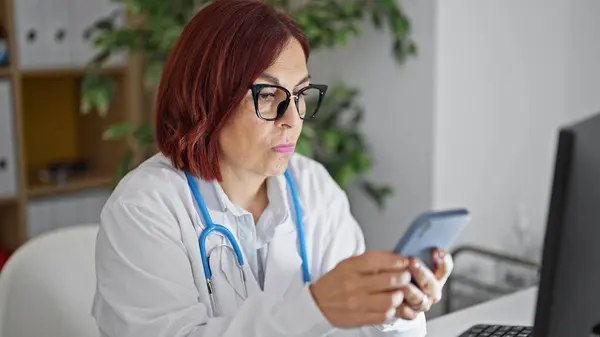 Middle age woman doctor using smartphone at the clinic