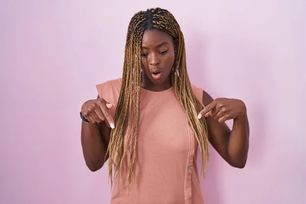 Африканская Американка Плетеными Волосами Стоит Розовом Фоне Указывая Вниз Пальцами — стоковое фото