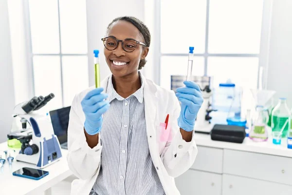 Laboratuvarda test tüpleri tutan Afrikalı Amerikalı kadın bilim adamı.