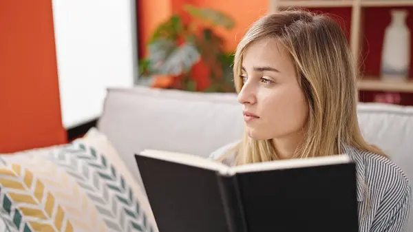 Young Blonde Woman Reading Book Sitting Sofa Home — Photo