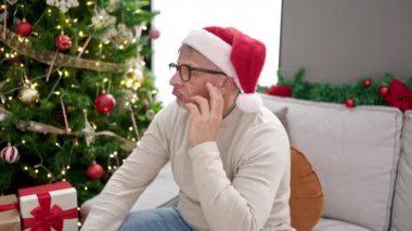 Noel şapkalı ve gözlüklü bir adam Noel 'i evde kutluyor.