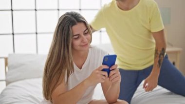 Yatak odasında akıllı telefon kullanan güzel bir çift.