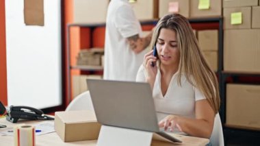 İki işçi, ofiste bilgisayarla akıllı telefondan konuşuyor.