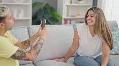 Kanepede oturan güzel bir çift evde akıllı telefondan fotoğraf çekiyor.
