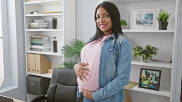 笑顔の若い妊婦は自信を持ってオフィスで働いている間に腹に触れ 産婦人とビジネスの成功を体現します — ストック動画