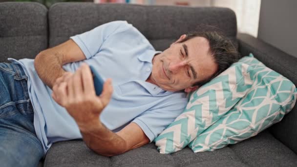 Medelålders Man Ligger Soffa Efterbehandling För Att Använda Smartphone För — Stockvideo