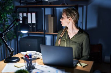 Geceleri ofiste çalışan genç sarışın bir kadın. Yan tarafa bakıyor, rahat bir görünüm takınıyor. Kendine güvenen bir gülümsemesi olan doğal bir yüzü var.. 