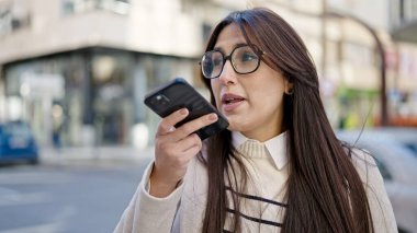 Genç, güzel İspanyol kadın sokakta akıllı telefonuyla sesli mesaj yolluyor.