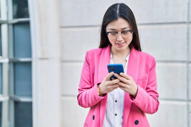 Sokakta akıllı telefon kullanan Çinli bir iş kadını.