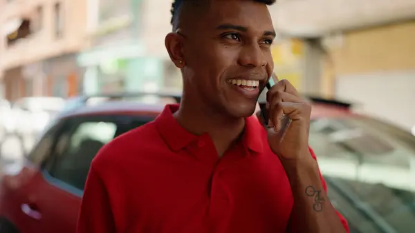 年轻的拉丁男人在街上用智能手机自信地微笑着 — 图库照片