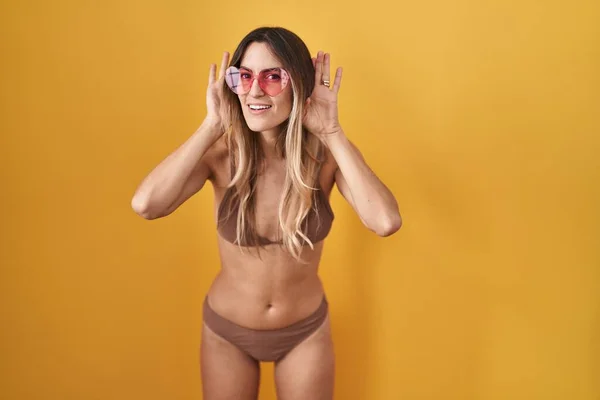 Jeune Femme Hispanique Portant Bikini Sur Fond Jaune Essayant Entendre — Photo