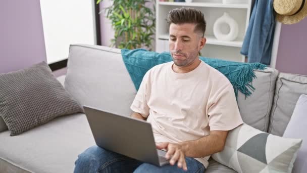 自宅でストレスを受けた若いヒスパニック系男性 ソファーに横たわり クッションで顔を覆い ノートパソコンを閉じ 屋内で不幸を表現する — ストック動画