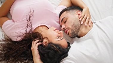 Man and woman couple lying on bed kissing at bedroom