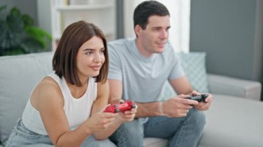 Evdeki kanepede oturmuş video oyunu oynayan güzel bir çift.