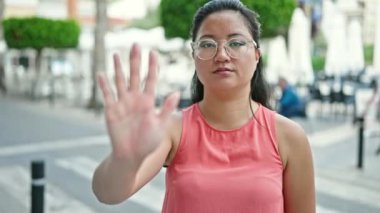 Genç Çinli bir kadın sokakta el hareketlerini durduruyor.