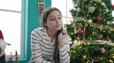 Genç, güzel, İspanyol bir kadın Noel 'i kutluyor. Ciddi bir ifadeyle evde oturuyor.