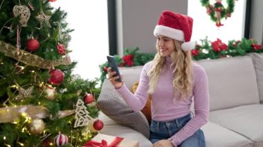 Genç sarışın kadın Noel süslemelerine video kaydediyor.