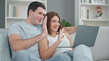 Kanepede birlikte oturan güzel bir çift evde video görüşmesi yapıyorlar.