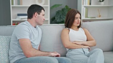 Güzel bir çift kanepede oturmuş birbirlerine sarılıyor ve gülümsüyor.