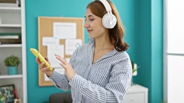 Genç bayan iş kadını ofiste müzik dinleyip dans ediyor.