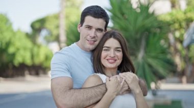 Güzel çift gülümsüyor. Parkta birbirlerine sarılıyorlar.