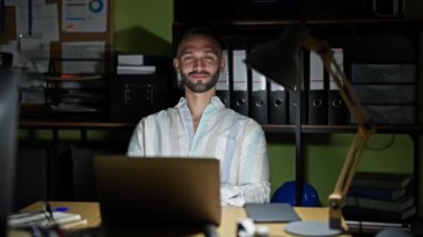 Genç İspanyol iş adamı ofiste dizüstü bilgisayar kullanarak el sıkışıyor.