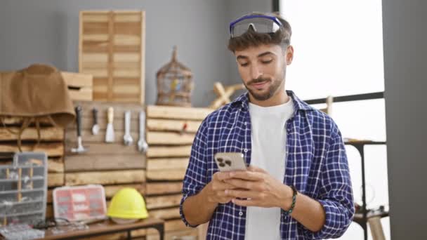 Sorrindo Jovem Árabe Homem Carpinteiro Profissional Alegremente Textos Seu Smartphone — Vídeo de Stock