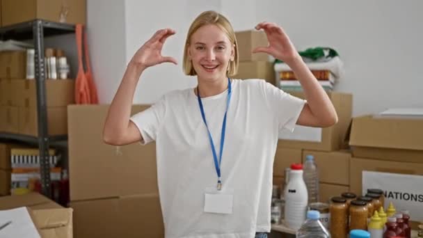 Joven Mujer Rubia Voluntaria Sonriendo Confiada Haciendo Gesto Corazón Centro — Vídeo de stock