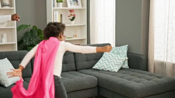 アフリカ系アメリカ人の父親と娘は 自宅でソファーで遊ぶスーパーヒーローの衣装を着て自信を持って微笑んでいる — ストック動画