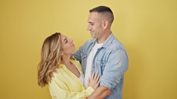 男性と女性カップルは孤立した黄色の背景の上に笑顔で抱き合う — ストック動画