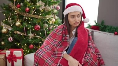 Genç, güzel, İspanyol bir kadın Noel şapkası takıyor ve evde ciddi bir ifade var.