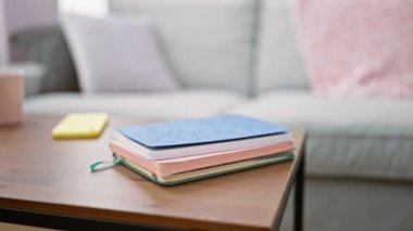 Young blonde woman reading book sitting on sofa at home