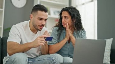 Erkek ve kadın, evde laptop ve kredi kartıyla alışveriş yapıyor.