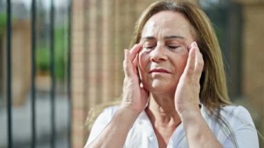 Orta yaşlı İspanyol kadın sokakta baş ağrısı çekiyor.