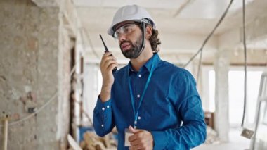 Genç İspanyol mimar inşaat alanında telsizle konuşuyor.