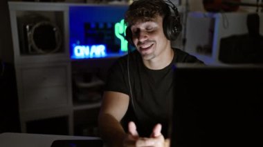 Yakışıklı, İspanyol asıllı genç bir adam, oyun odasında bir flamalı, video oyunları oynarken dijital bir sohbete dalıp, internette sırıtarak konuşuyor.