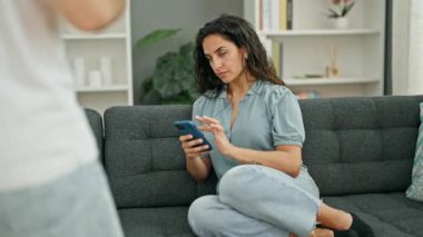 Kadın ve erkek akıllı telefon kullanıyor. Evde kahve içiyorlar.