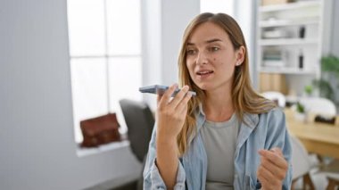 Çekici sarışın iş kadını ofiste çalışırken akıllı telefondan kendine güvenen bir sesli mesaj gönderiyor.