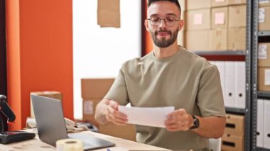Genç İspanyol adam ecommerce işi. Ofisteki karton kutuda talimatları paketliyor.