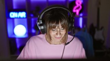 Young beautiful hispanic woman streamer playing video game using computer at gaming room