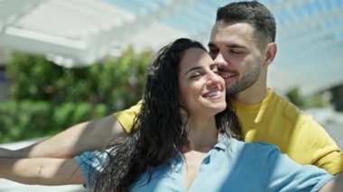 Erkek ve kadın çift parkta kollarını açarak birlikte duruyorlar.