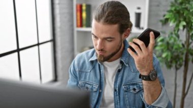 Genç İspanyol iş adamı ofiste çalışan akıllı telefonuyla sesli mesaj gönderiyor.