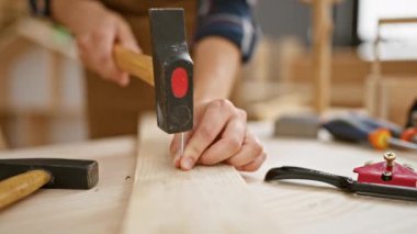 Güçlü kadın marangozun elleri, profesyonel marangozluk atölyesinde tahta çiviye batırdı.